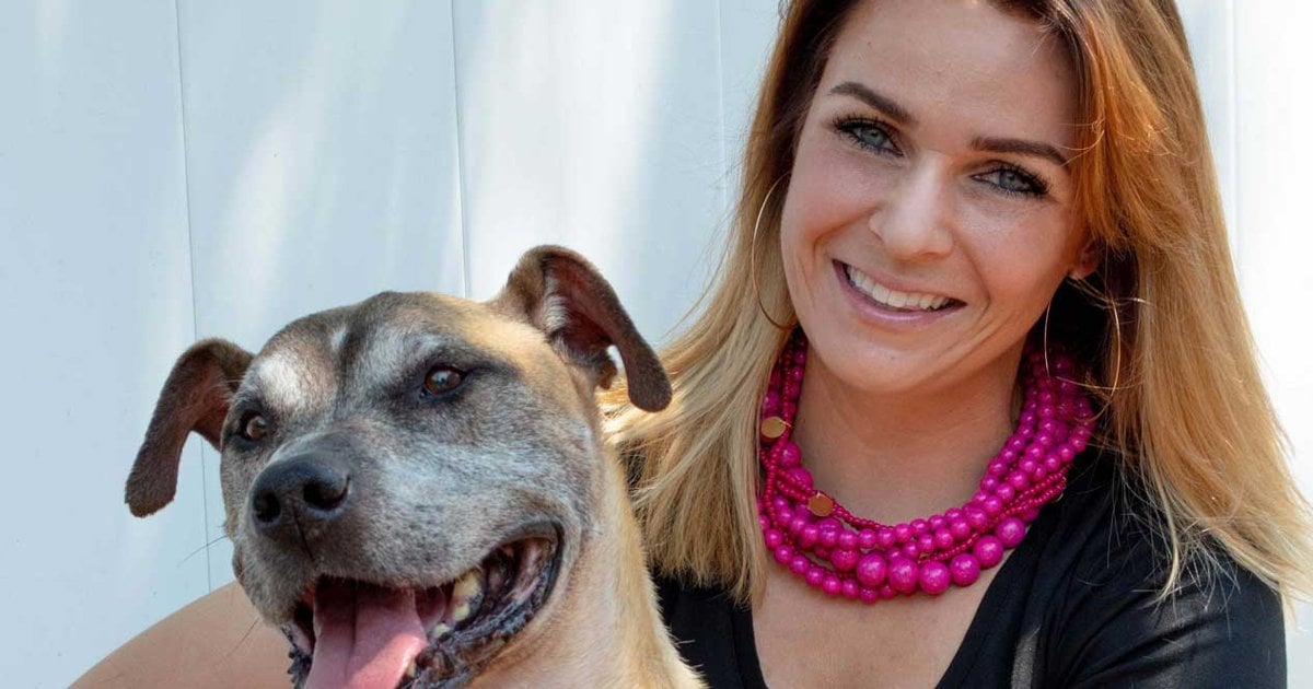 Paulina Beck, owner and Master Dog Trainer at The Mannered Mutt in Conroe, TX, smiling with a tan dog